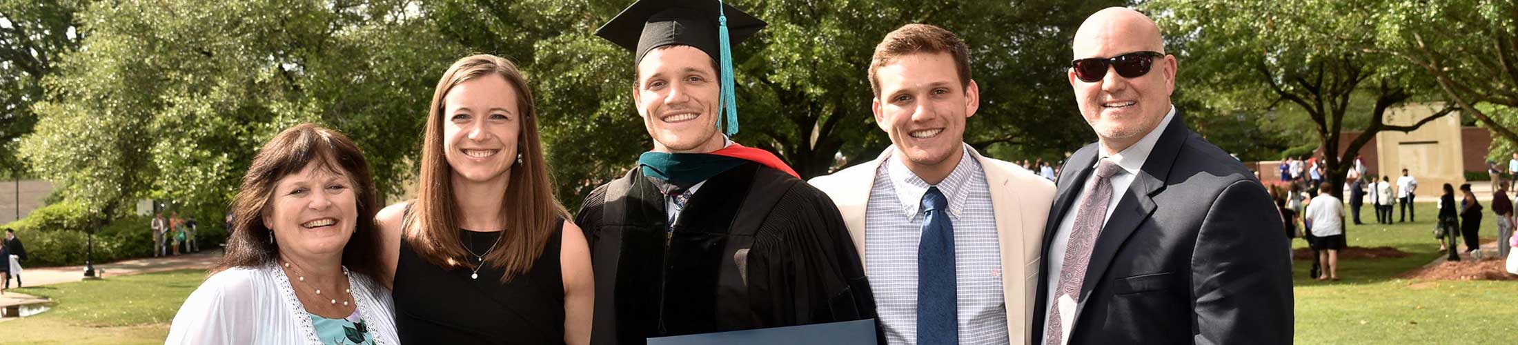 Graduate in cap and gown with family outside