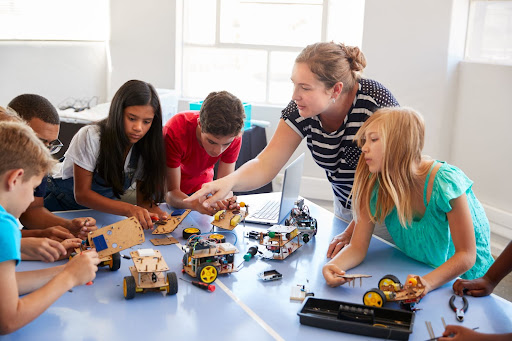 Teacher working with kids building cars.