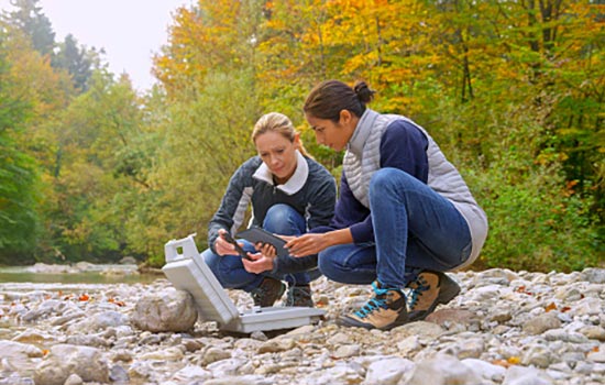 people working with rocks by a river