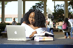 Female writing outside at table.