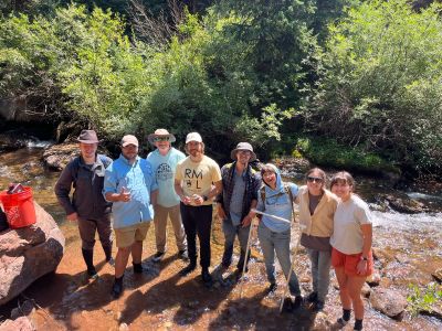 Seven students standing in a Colorado Stream with Dr. Lehrter looking up 