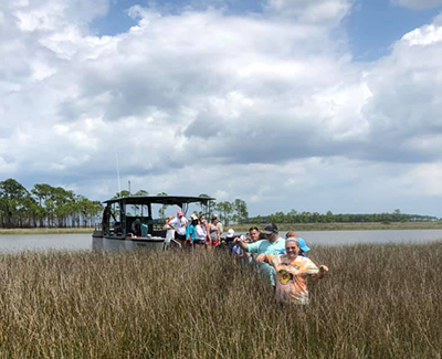 Marine sciences students out on a boat and in the marsh working.