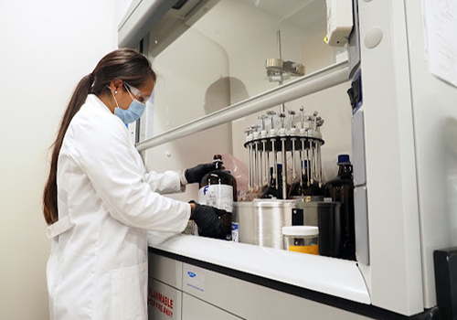 Student working in lab with white coat on.