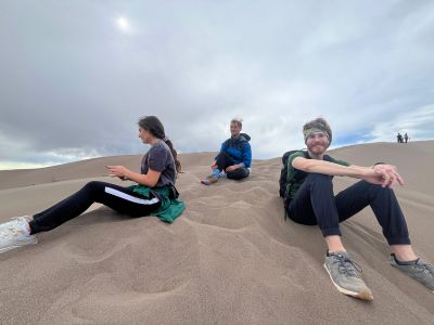 Three students sitting on sand dunes