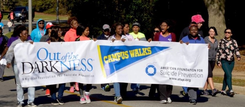 Students walking at out of darkness march holding banner