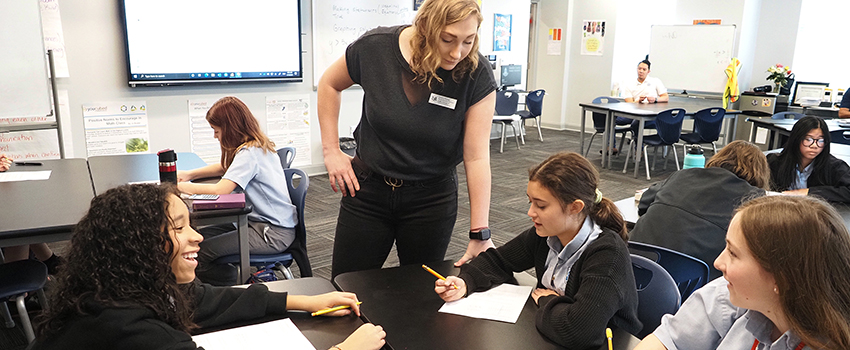 Student teacher working with students in classroom with safety glasses on.