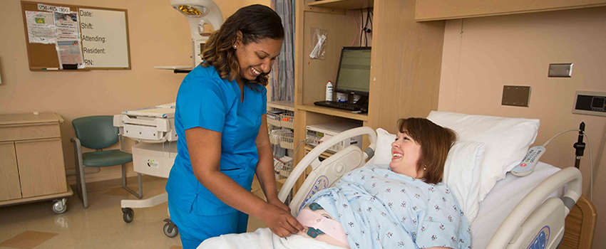 Nurse working with pregnant woman laying in hospital bed