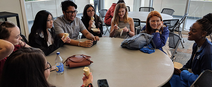 Honors students sitting around table in Student Center talking and eating ice cream