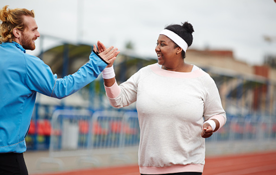 A male trainer high fiving a female on an outdoor track