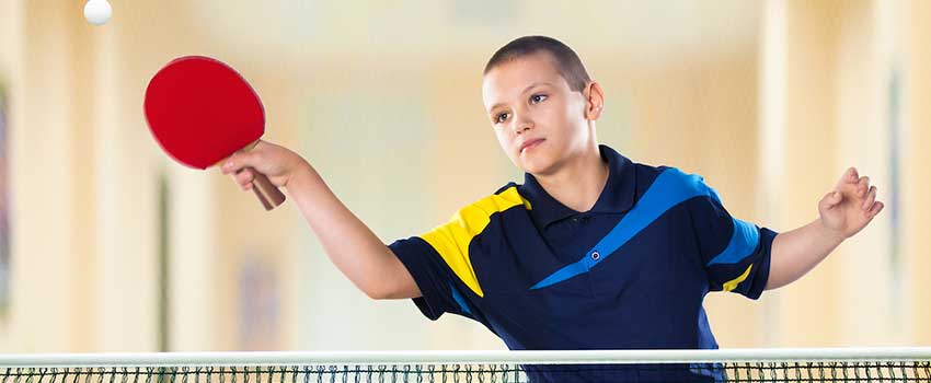 Young boy playing ping pong.