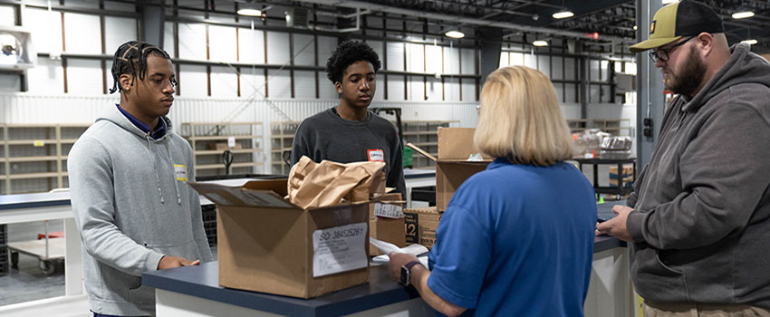 USA staff working with students in stockroom in job shadow day.