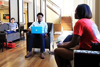 People working on laptops in a common area in housing.