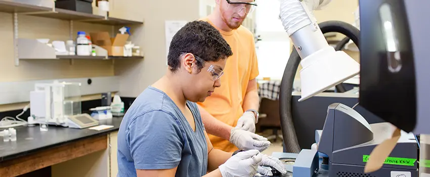 Two students working in lab with microscopes.