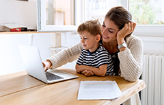 Mother with child in her lap looking at laptop